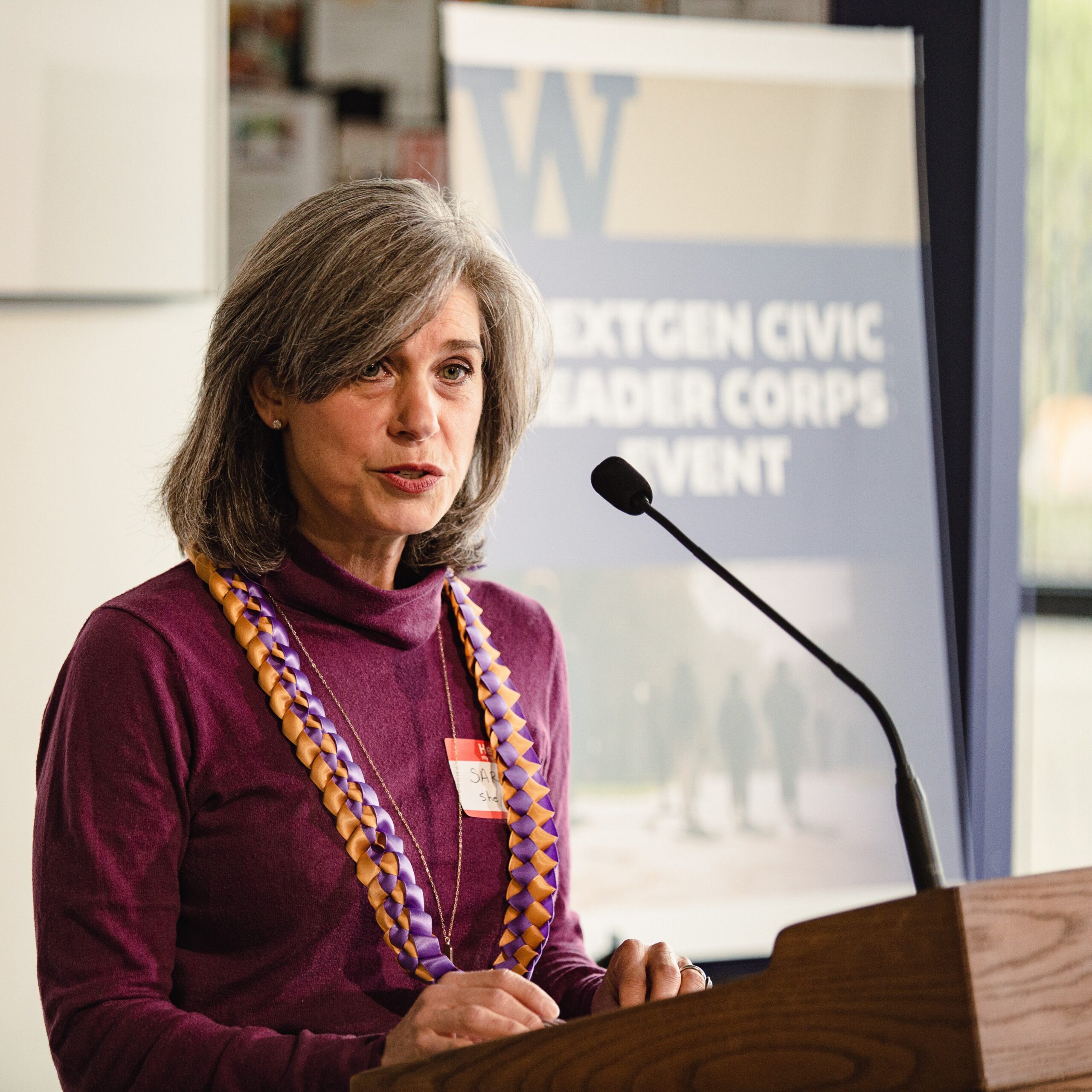A woman stands behind a podium while speaking to an audience