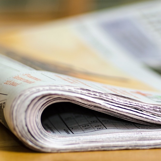A folded newspaper sits on a table