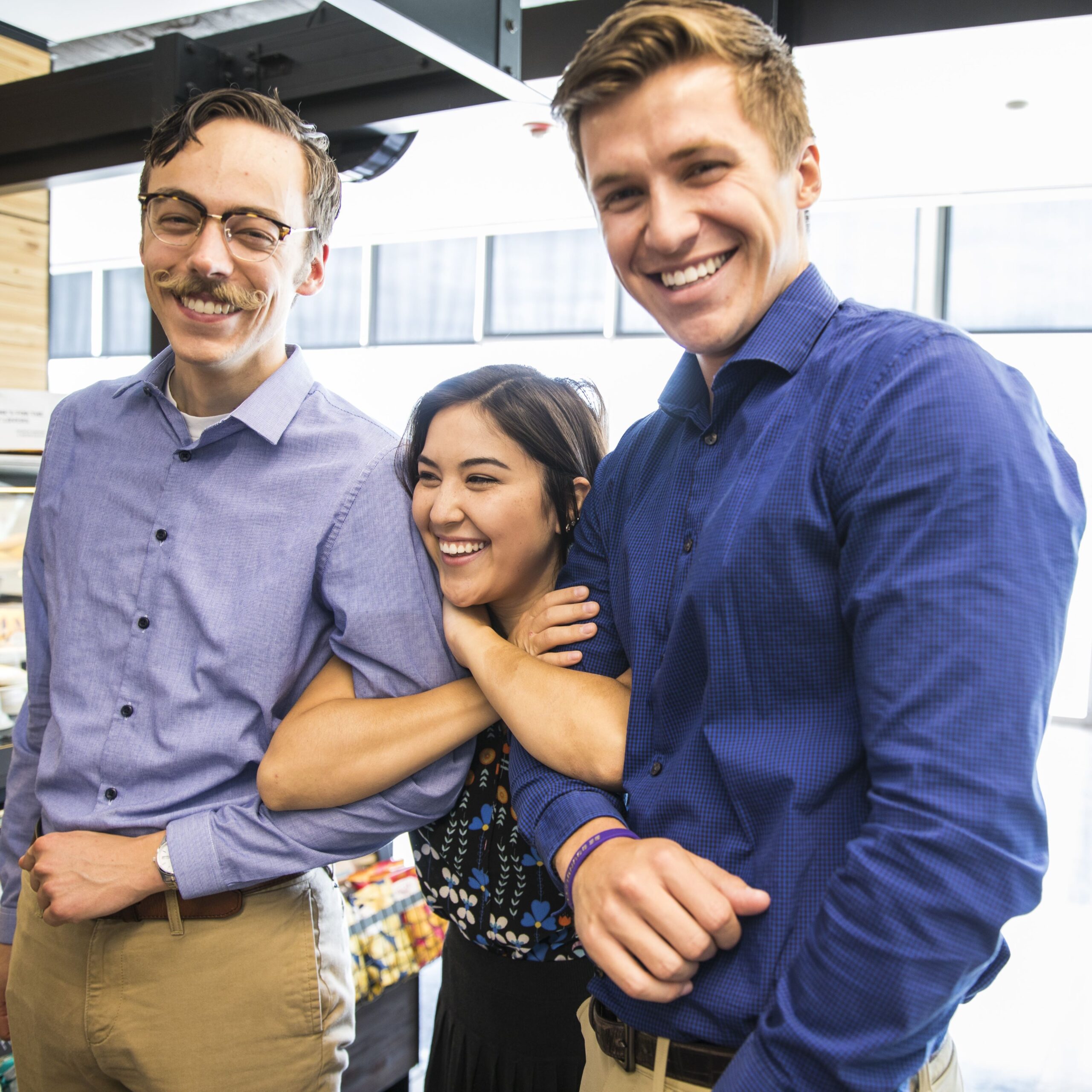 Two men and a women lock arms while smiling