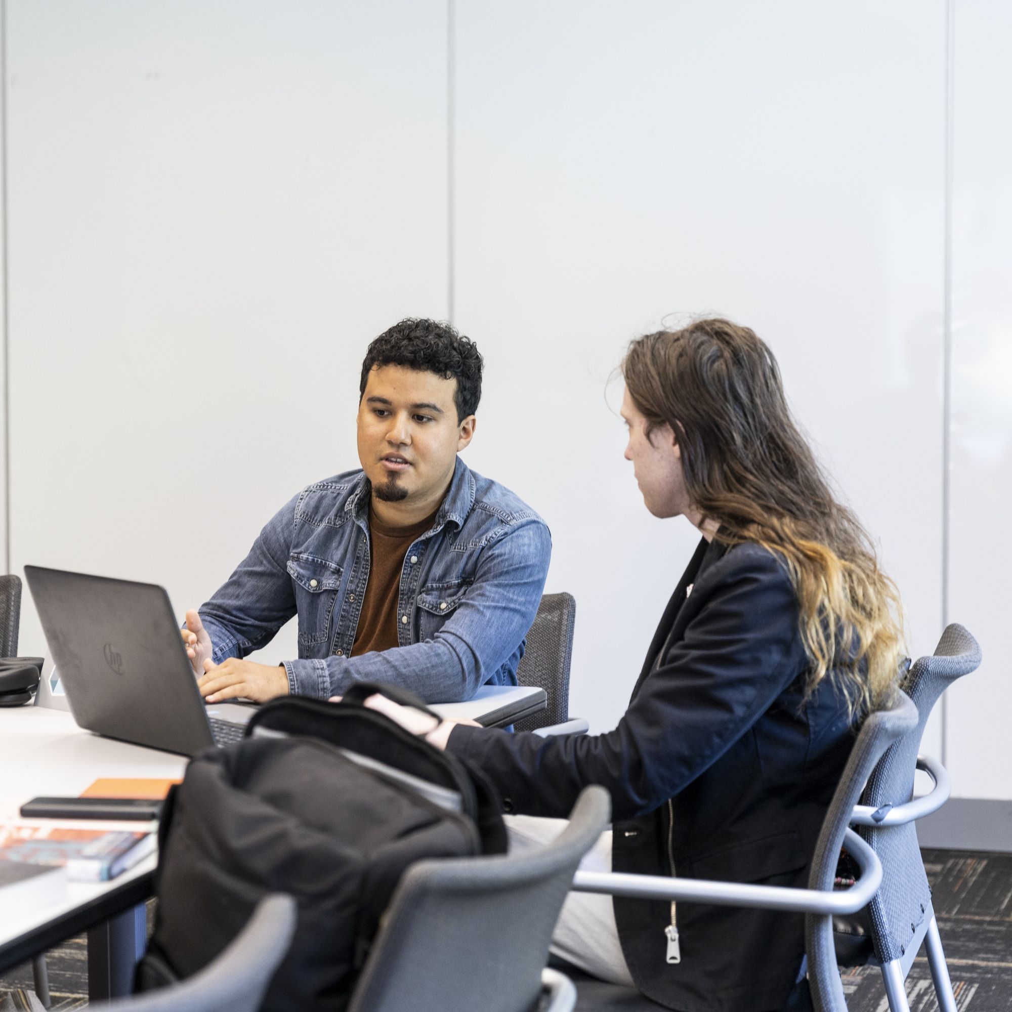 Two students work collaboratively on a project while seated at a table
